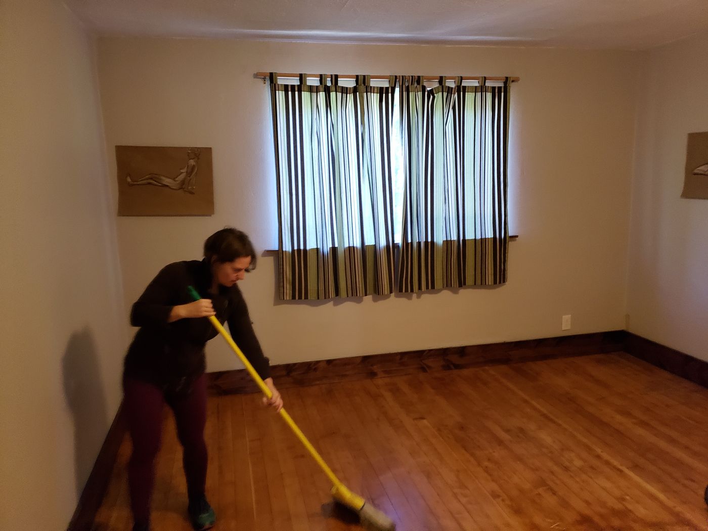 Crew member sweeping an empty room after a move-out